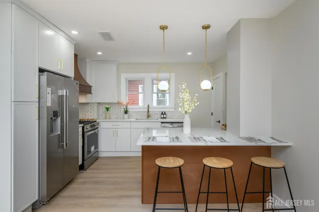 a kitchen with stainless steel appliances granite countertop a sink a stove a refrigerator and island with wooden floor