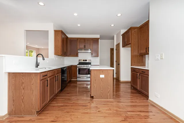 a large kitchen with stainless steel appliances granite countertop a refrigerator a sink dishwasher a stove with wooden cabinets and floor