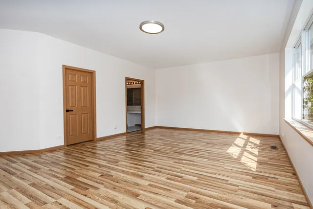 a view of an empty room with wooden floor and window