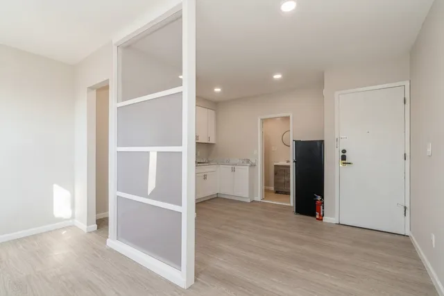 an empty room with wooden floor and entrance to ceiling window