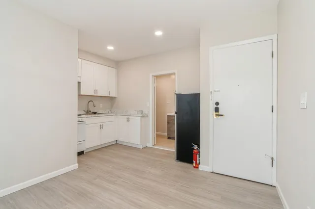 a kitchen with a refrigerator and white cabinets