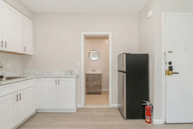 a view of a kitchen with refrigerator and white cabinets