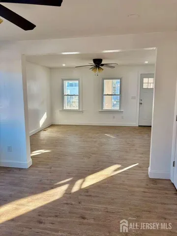 a view of empty room with wooden floor and fan
