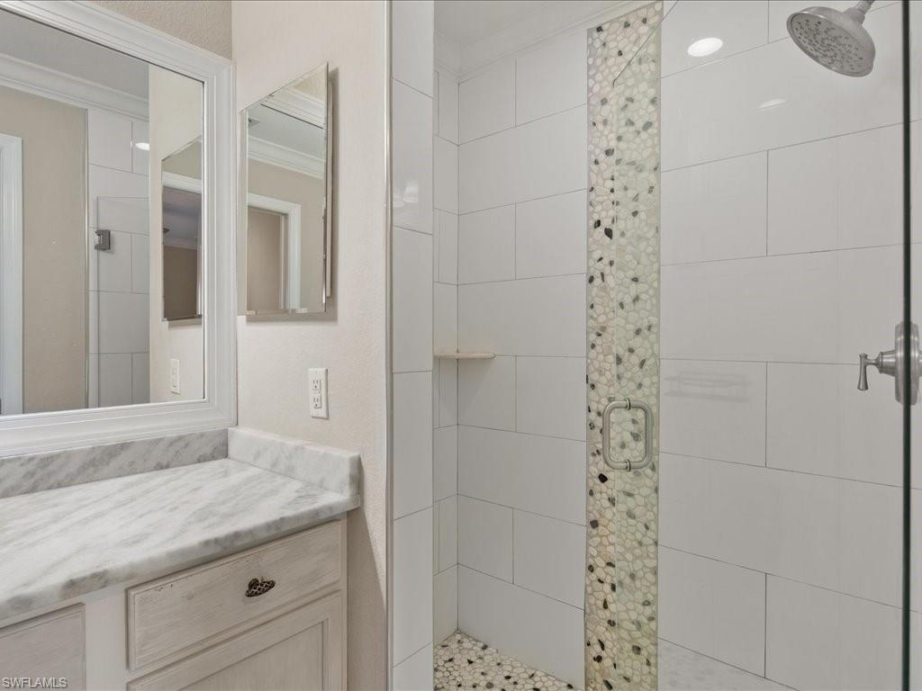 9719 Acqua Court, Unit 218 Naples, FL 34113 - Photo 15 of 23 Full bathroom with crown molding, a stall shower, and vanity