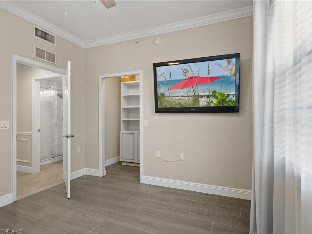 9719 Acqua Court, Unit 218 Naples, FL 34113 - Photo 17 of 23 Unfurnished bedroom featuring wood tiled floors, a walk in closet, crown molding, and a ceiling fan