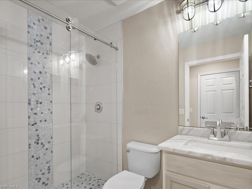 9719 Acqua Court, Unit 218 Naples, FL 34113 - Photo 18 of 23 Bathroom featuring a textured wall, a shower stall, and vanity