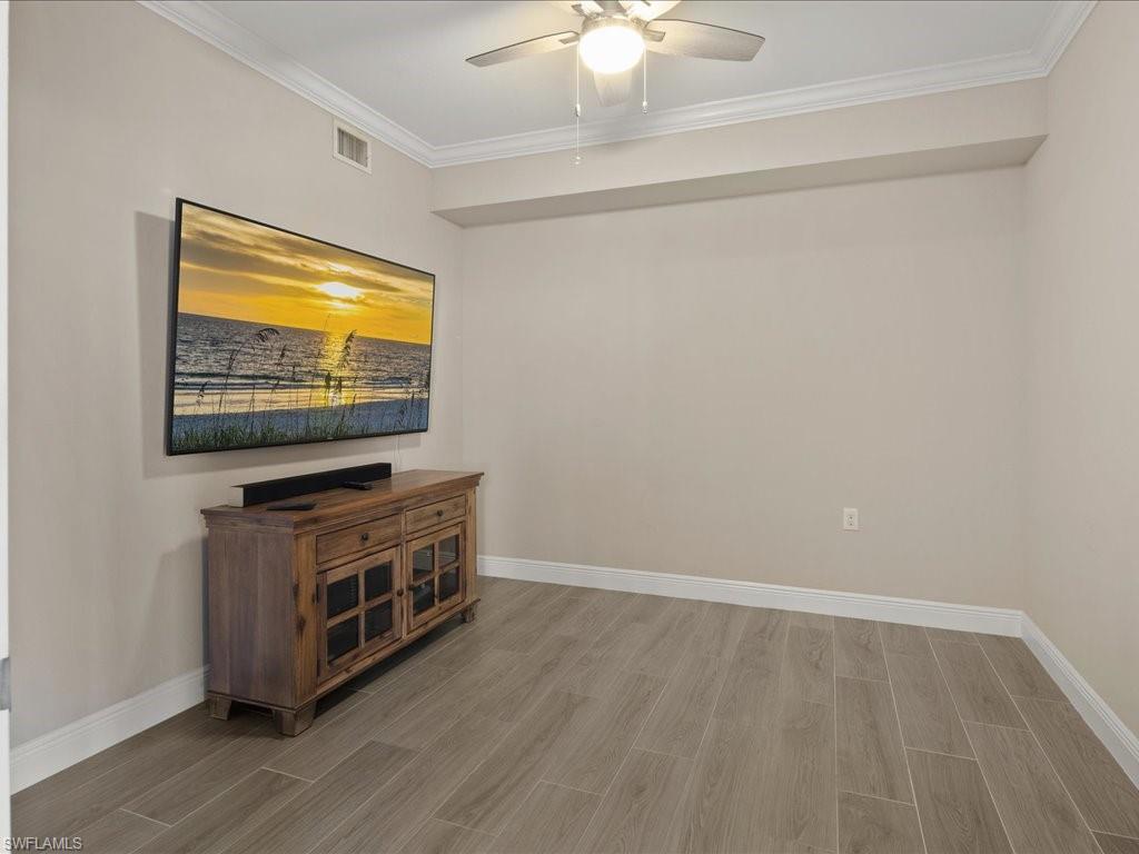 9719 Acqua Court, Unit 218 Naples, FL 34113 - Photo 19 of 23 Unfurnished room with wood finish floors, a ceiling fan, and crown molding