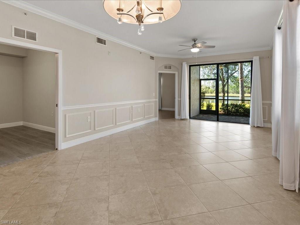 9719 Acqua Court, Unit 218 Naples, FL 34113 - Photo 3 of 23 Unfurnished room featuring a decorative wall, wainscoting, crown molding, a ceiling fan, and a chandelier