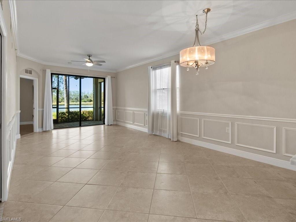 9719 Acqua Court, Unit 218 Naples, FL 34113 - Photo 4 of 23 Empty room with a wainscoted wall, a ceiling fan, crown molding, a water view, and a decorative wall
