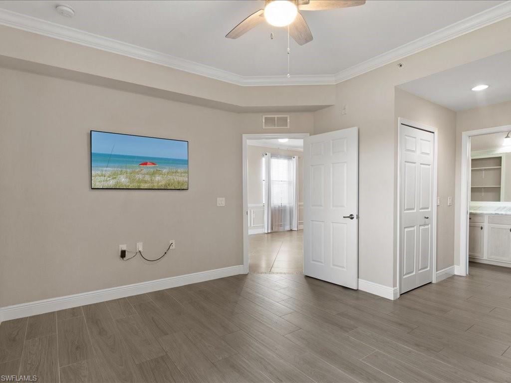9719 Acqua Court, Unit 218 Naples, FL 34113 - Photo 10 of 23 Unfurnished bedroom with crown molding, wood finished floors, ceiling fan, and ensuite bath