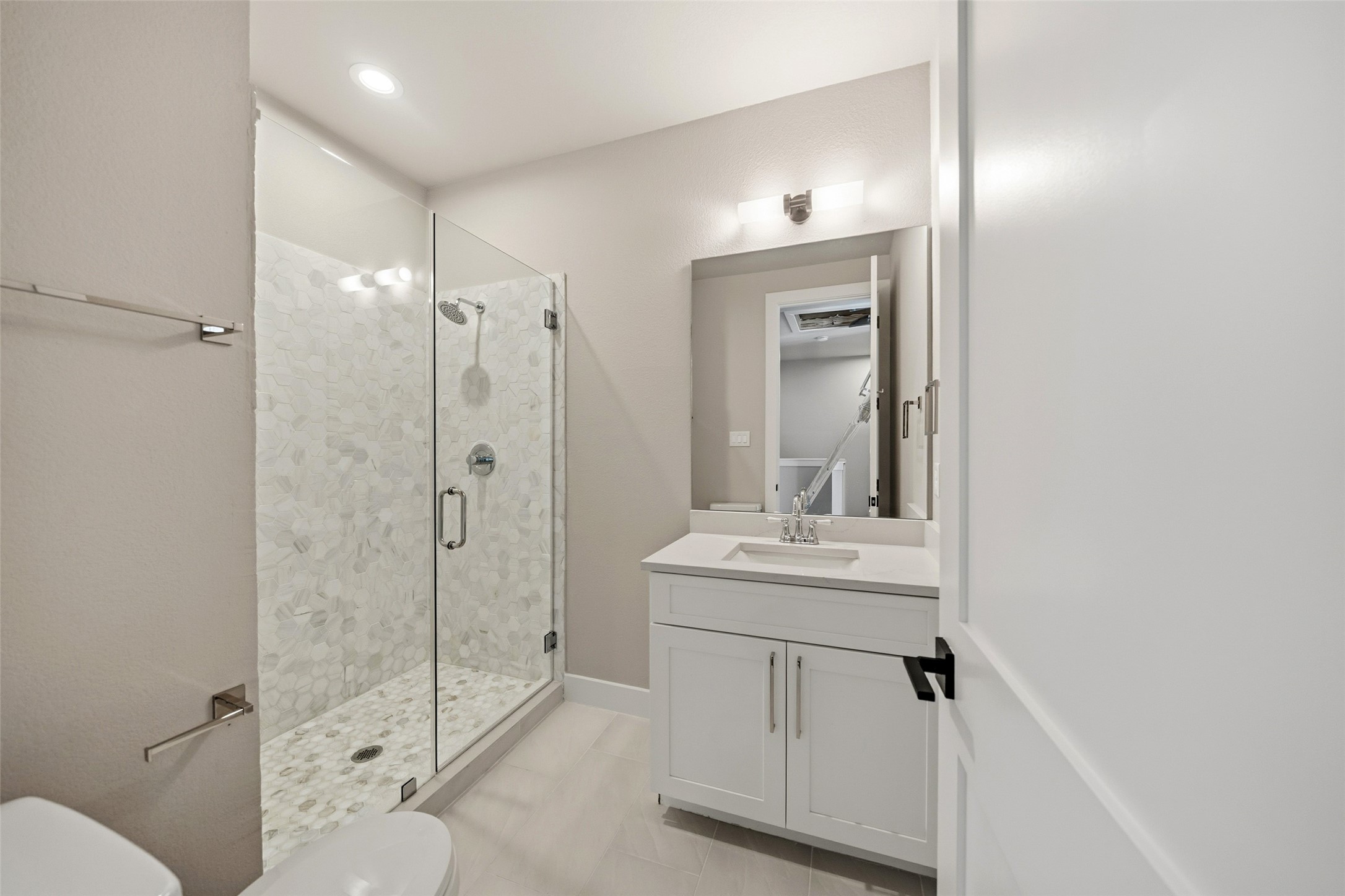 3422 Elser Street Houston, TX 77009 - Photo 17 of 26 This bathroom features a modern design with a glass-enclosed shower, elegant white vanity, and contemporary fixtures. The neutral color palette and recessed lighting create a bright and inviting space.
