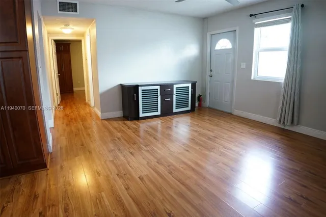 an empty room with wooden floor and windows