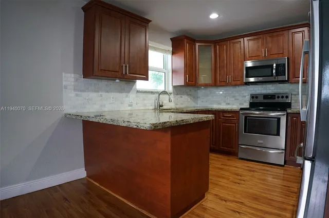 a kitchen with stainless steel appliances granite countertop wooden cabinets a stove top oven a sink and dishwasher