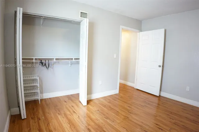 a view of an empty walk in closet with wooden floor