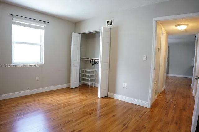 an empty room with wooden floor & closet area