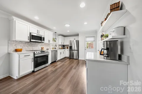 a kitchen with granite countertop a stove top oven a sink dishwasher and a refrigerator with wooden floor