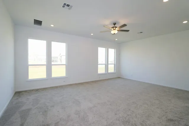 an empty room with windows and ceiling fan