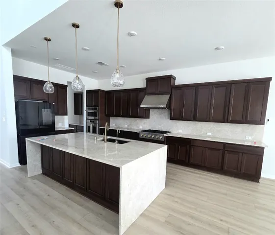 a large kitchen with stainless steel appliances a large counter top a sink and a stove