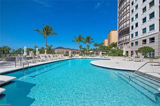 a view of a swimming pool with a lawn chairs under an umbrella