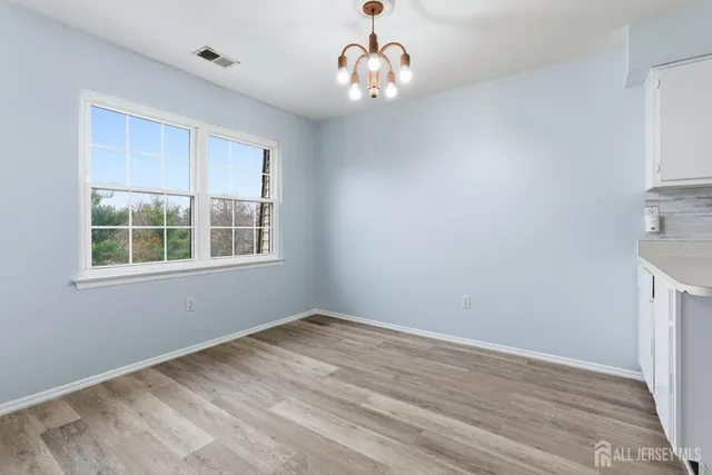 a kitchen with white cabinets and wooden floor