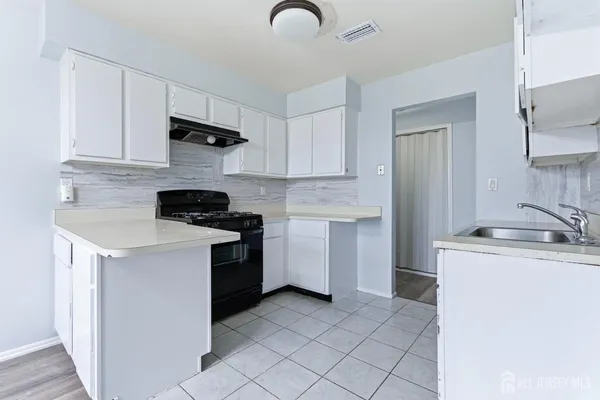 a kitchen with white cabinets and black appliances