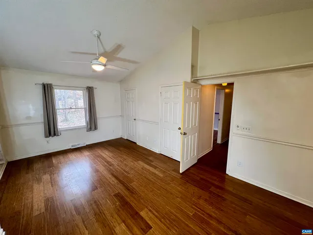 an empty room with wooden floor cabinet and windows