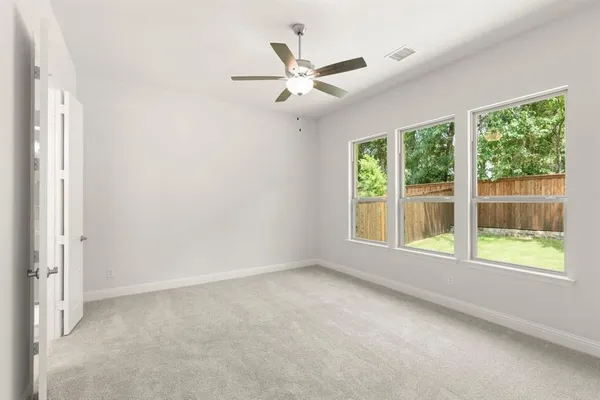 an empty room with windows and ceiling fan