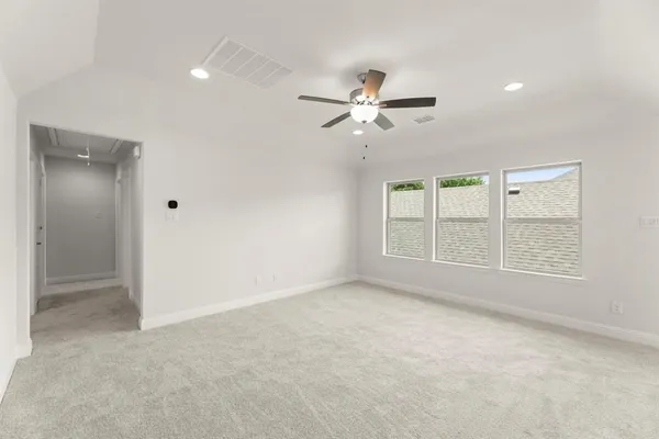 an empty room with chandelier fan and windows