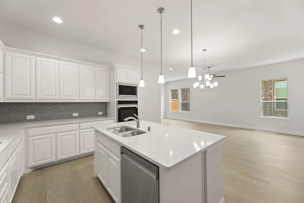a kitchen that has a sink a microwave a stove and cabinets