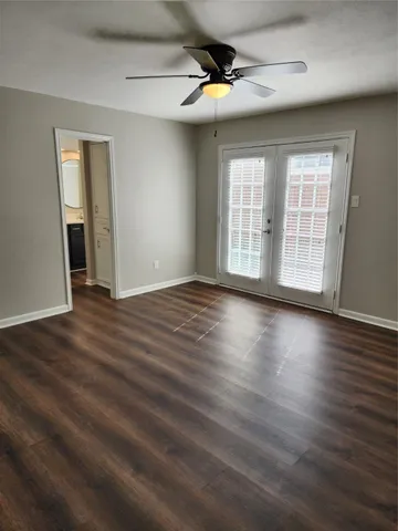 an empty room with wooden floor fan and windows