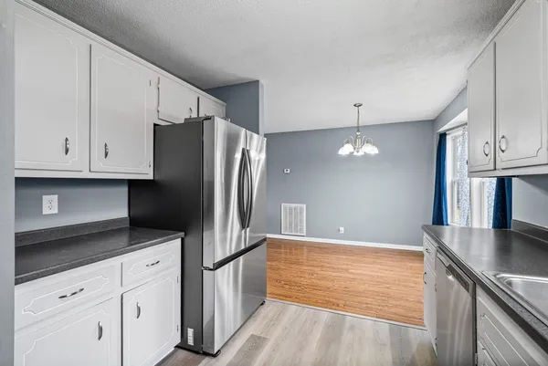 a kitchen with stainless steel appliances granite countertop a refrigerator a stove and white cabinets with wooden floors