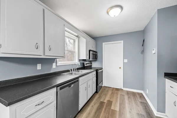 a kitchen with granite countertop cabinets stainless steel appliances a sink and wooden floor