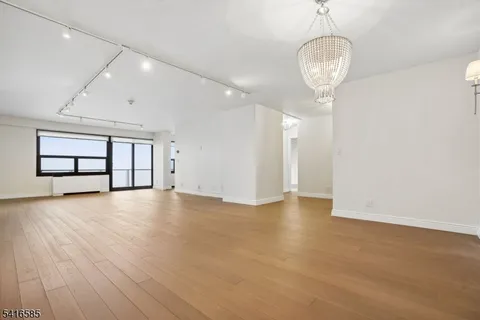 a view of empty room with wooden floor and chandelier