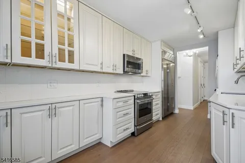 a kitchen with stainless steel appliances white cabinets and a stove top oven