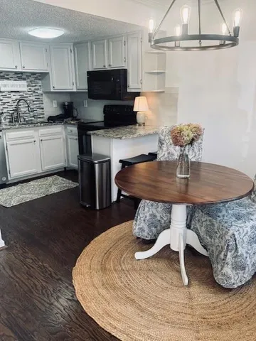a kitchen with stainless steel appliances granite countertop a table chairs sink and cabinets