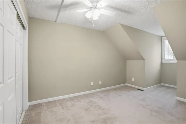 an empty room with a chandelier fan and windows