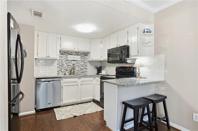 a kitchen with granite countertop a refrigerator stove microwave and sink