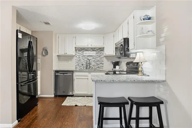 a kitchen with granite countertop white cabinets and stainless steel appliances