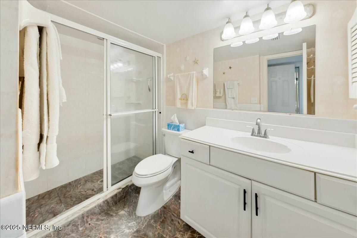 8090 Florida A1A, Unit 102 St. Augustine, FL 32080 - Photo 11 of 49 a bathroom with a sink toilet a mirror and shower