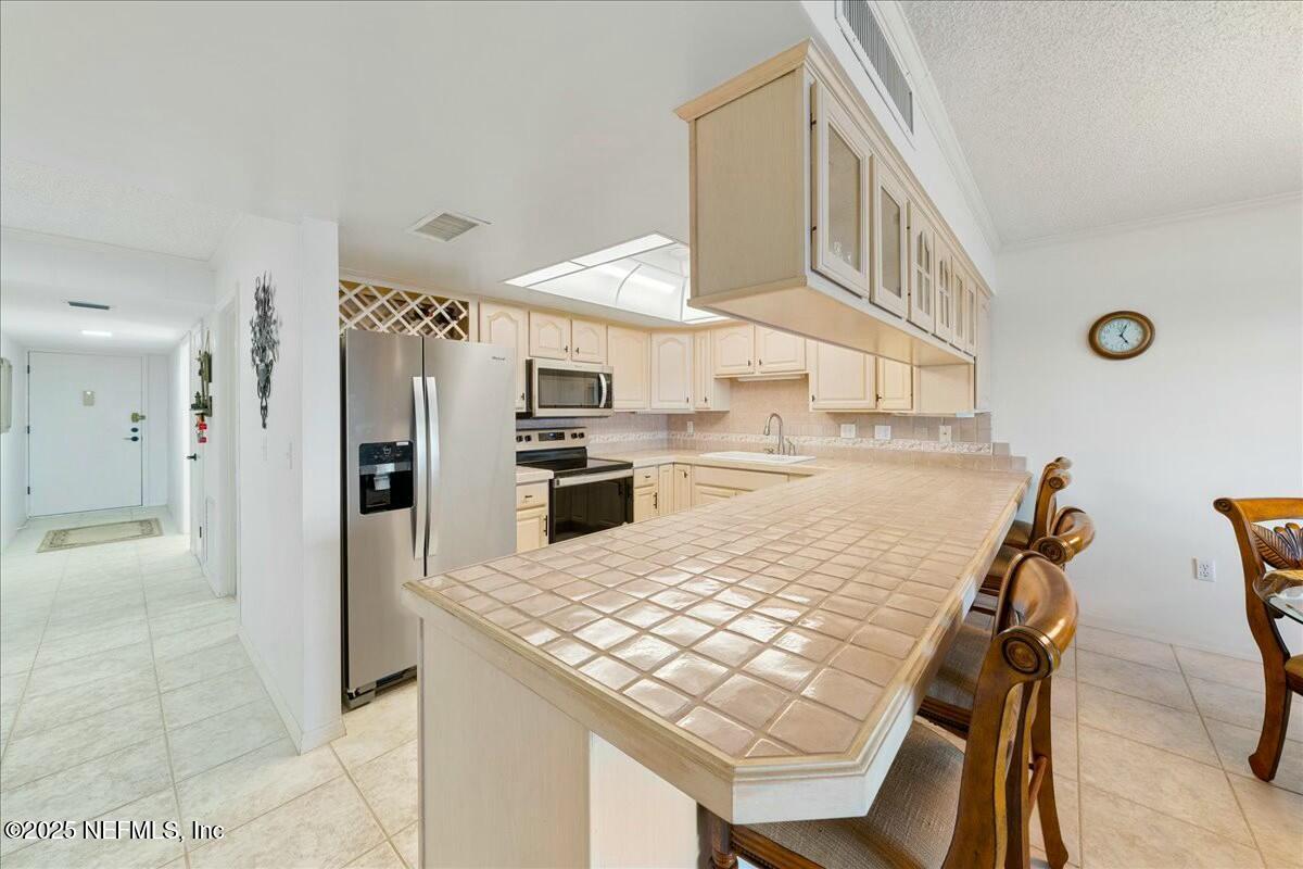 8090 Florida A1A, Unit 102 St. Augustine, FL 32080 - Photo 20 of 49 a kitchen with stainless steel appliances kitchen island a table chairs sink and cabinets