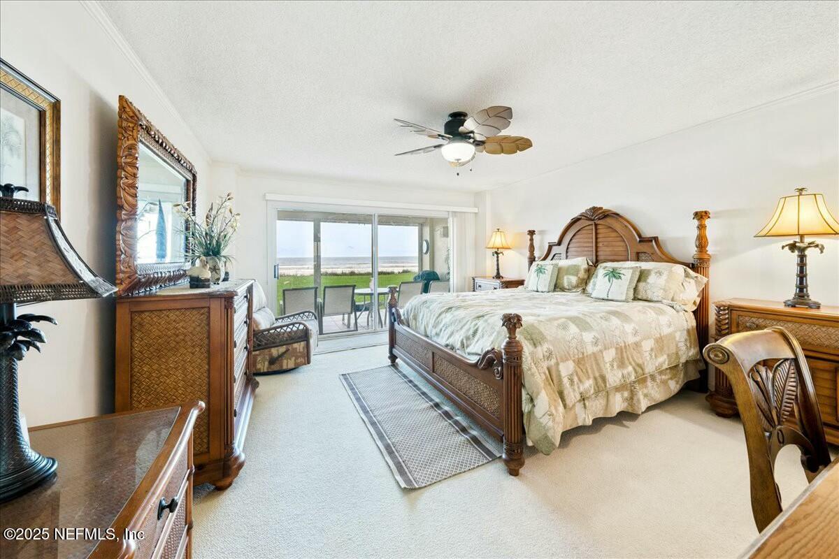 8090 Florida A1A, Unit 102 St. Augustine, FL 32080 - Photo 8 of 49 a spacious bedroom with a bed a chandelier and a large window