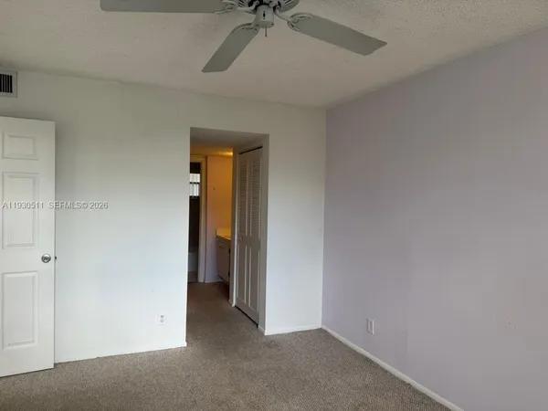 an empty room with a ceiling fan and carpet