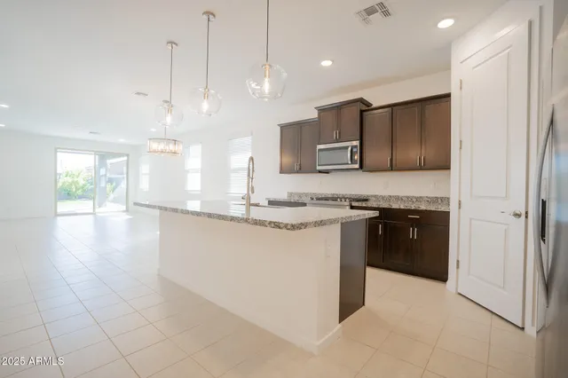 a kitchen with stainless steel appliances granite countertop a sink a stove and a refrigerator