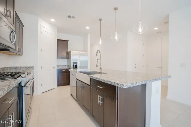 a large kitchen with granite countertop a large counter top stainless steel appliances and cabinets