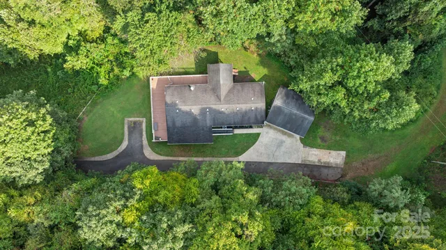 an aerial view of a house with outdoor space and trees all around