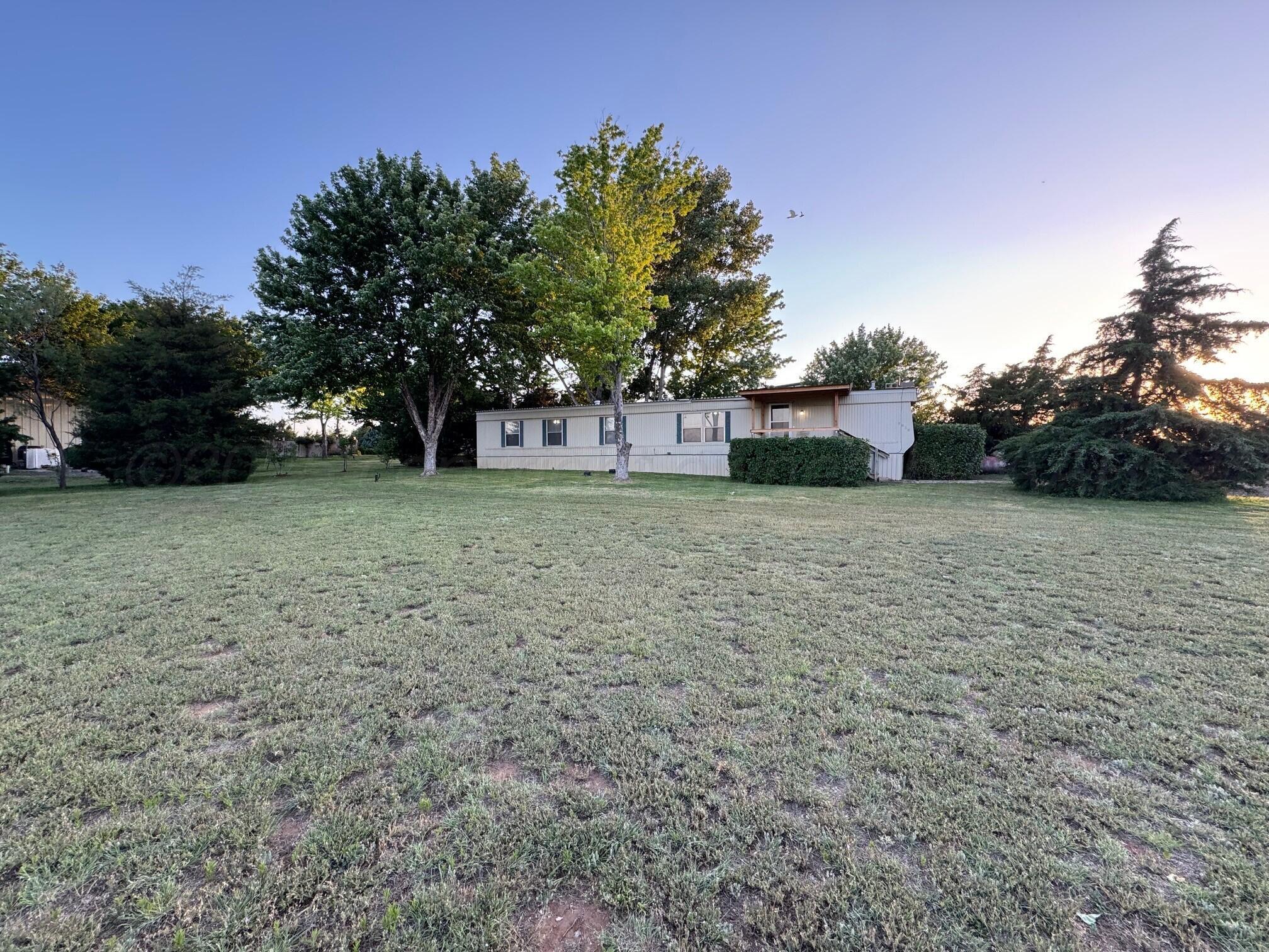a view of a yard with trees in front of it