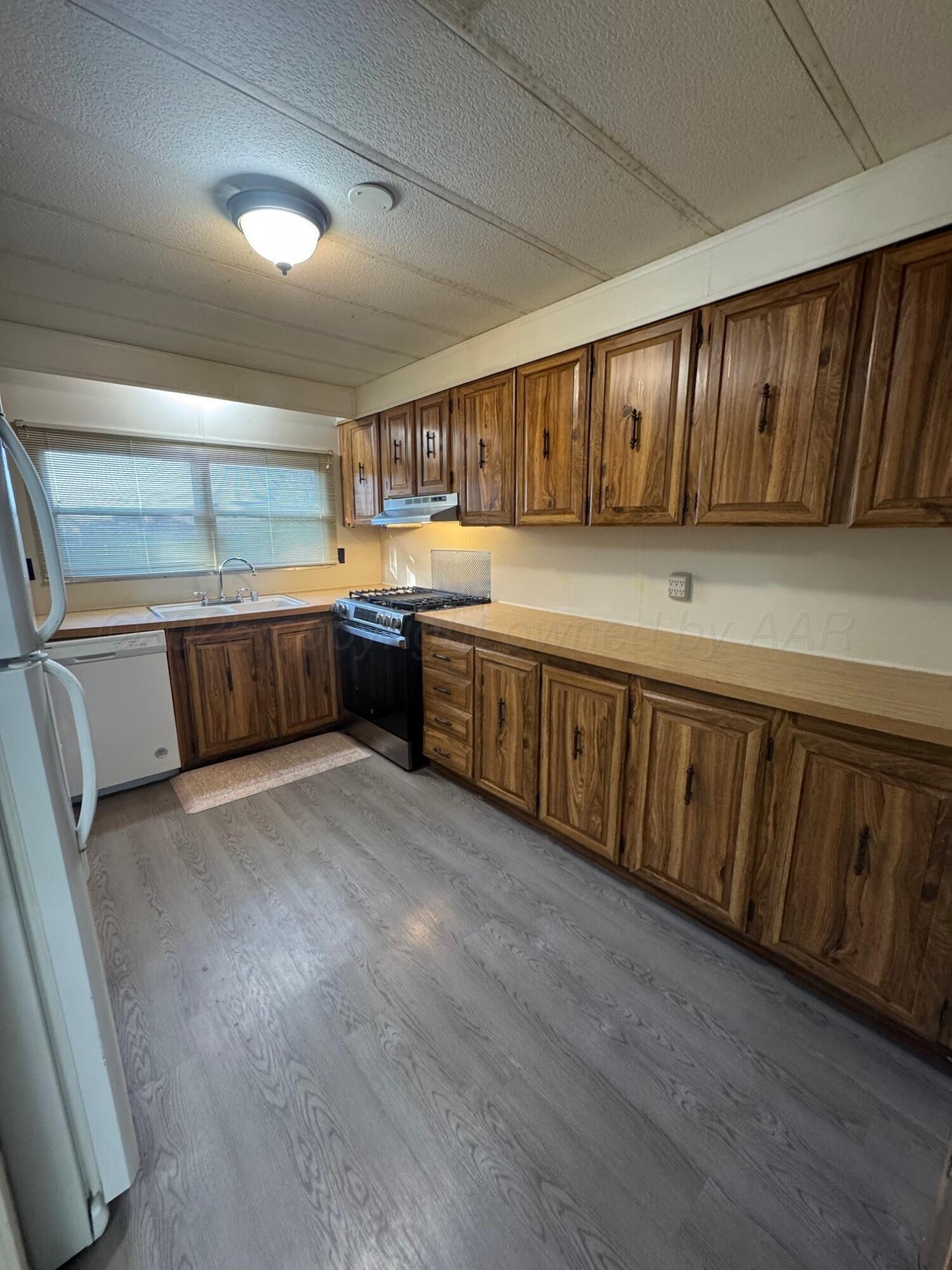 9705 Broadway Drive Amarillo, TX 79108 - Photo 4 of 10 a kitchen with stainless steel appliances granite countertop a sink a stove cabinets and wooden floor