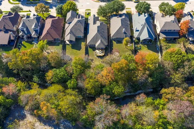 an aerial view of residential houses with outdoor space and trees