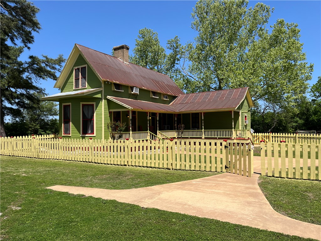 Charming 1860's farm house front view, with covered porch, and picket fenced front yard, with metal roof
