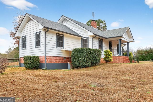 a view of a house with a yard and lawn chairs under an umbrella